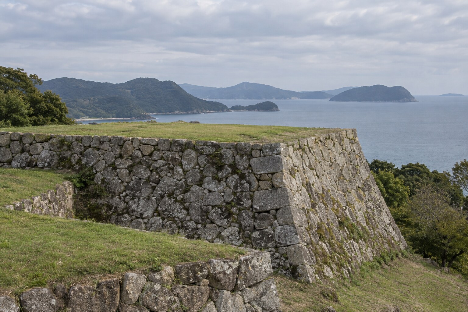 海沿いの城の石垣と天守台を表した想像図。発掘現場や当時の唐津城の復元図ではない（AI生成イメージ）